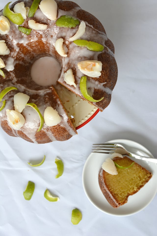 overhead view of a sliced Lime and Lychee Bundt Cake with a portion placed beside it on a saucer plate, accompanied by a fork