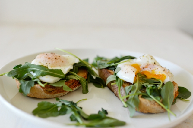 two toasted bread with poached eggs and herbs on top 