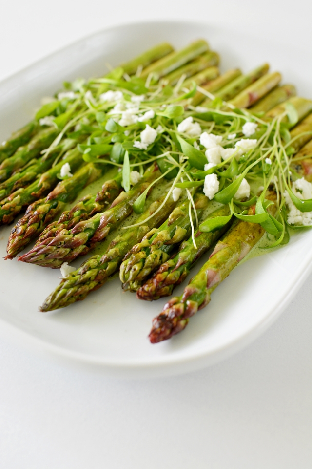 close up view image of asparagus stem topped with fresh parsley and coriander, drizzled with dressing