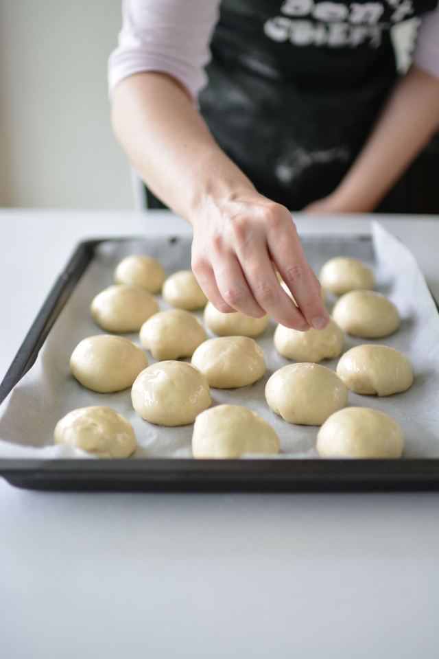a woman skillfully shaping dough balls on a baking tray in preparation for baking