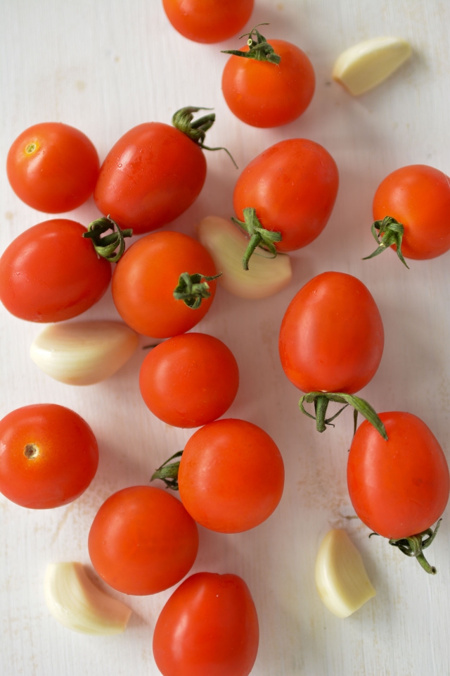 top view image of  fresh cherry tomatoes and cloves of garlic 
